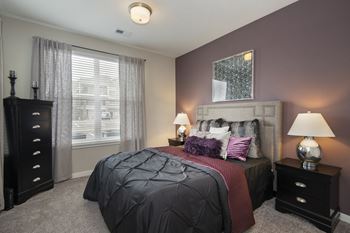 A bedroom with a bed and two dressers and a window